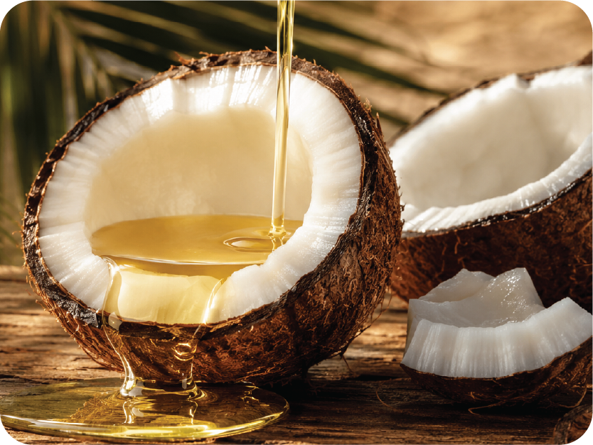Coconut being sliced open with oil being poured into a glass.