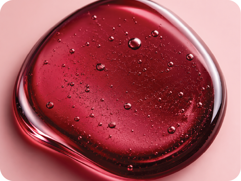 Close-up of a red gel or cream with bubbles on a pink background